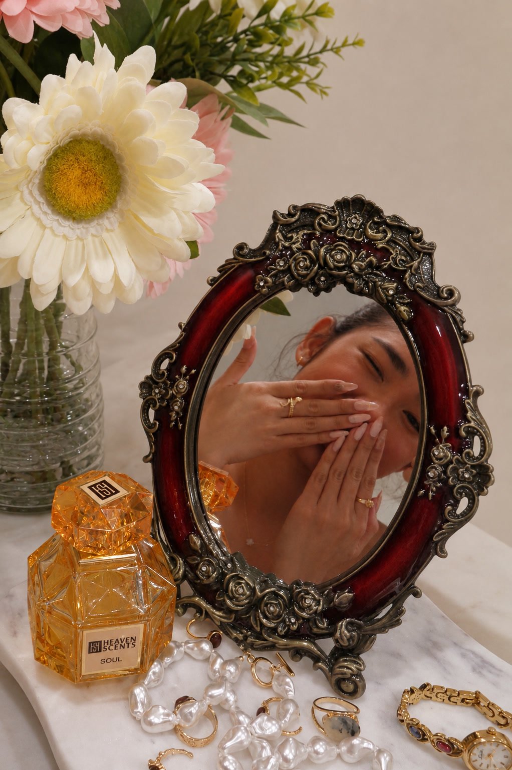 A Roselia manicure reflected in an ornate mirror beside perfume and pearls