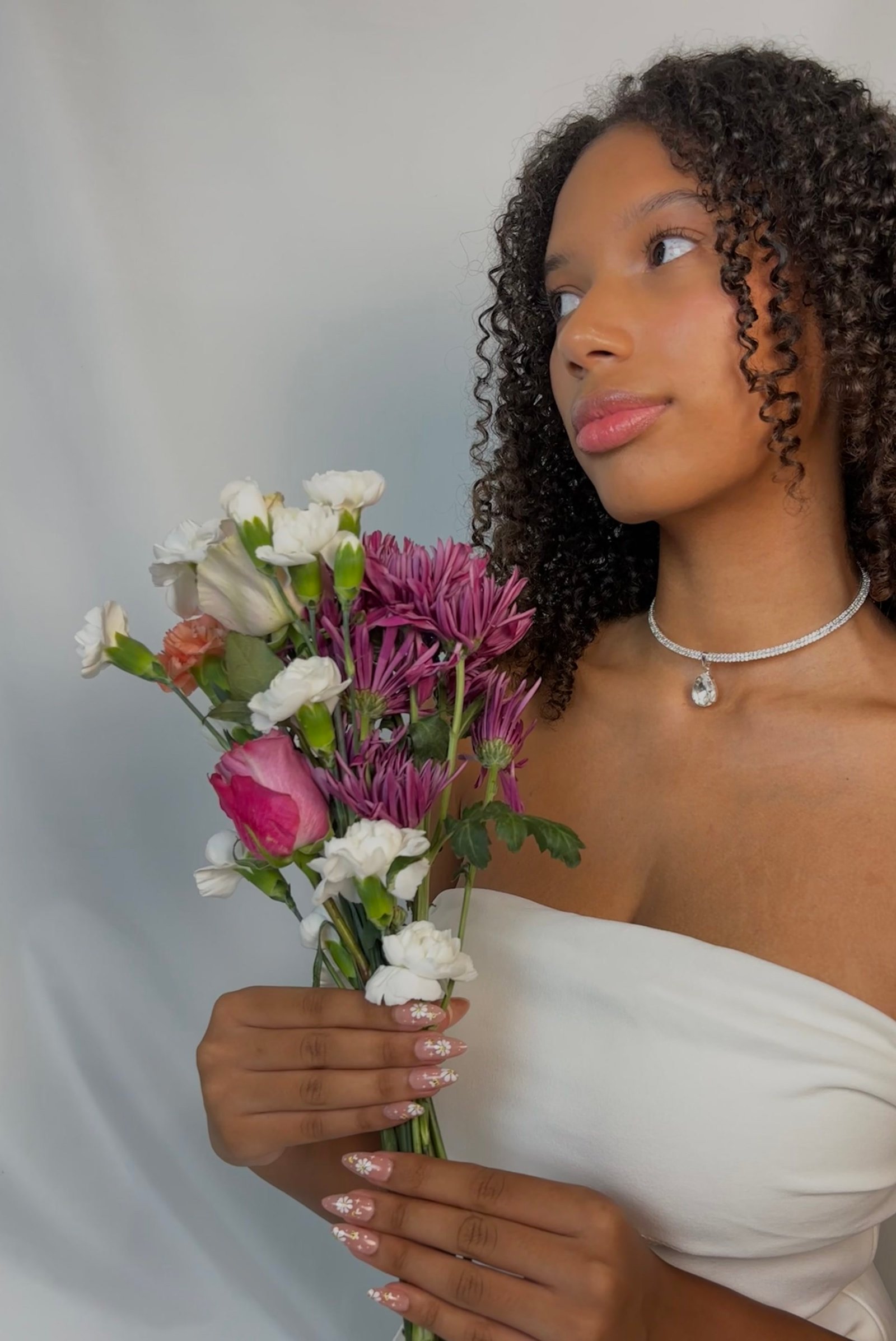 Someone holding a bouquet of flowers, wearing daisy painted Roselia nails